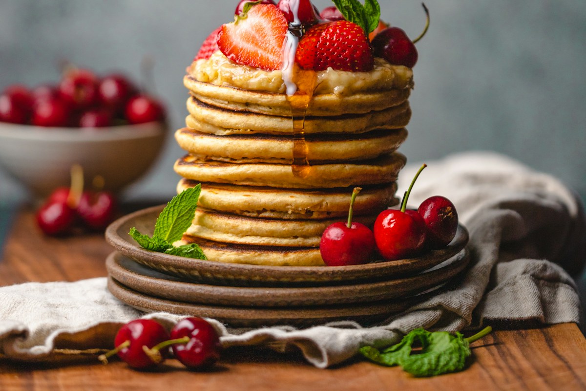 Stack of golden pancakes topped with fruit and syrup